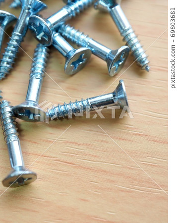 Silver screws and wooden board background Silver screws and wooden board background 69803681