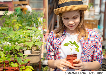 Adorable teen girl kid in hat with seedlings Adorable teen girl kid in hat with seedlings 69804084