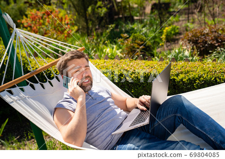 freelancer lies in hammock, working on computer freelancer lies in hammock, working on computer 69804085