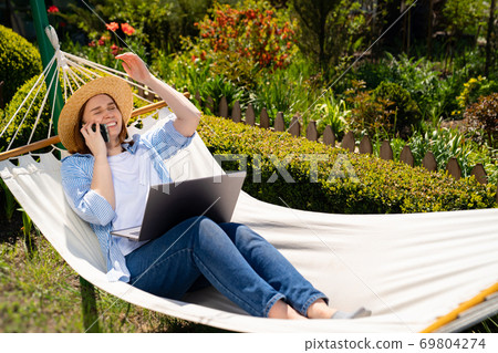 woman lies in hammock, answers phone call woman lies in hammock, answers phone call 69804274