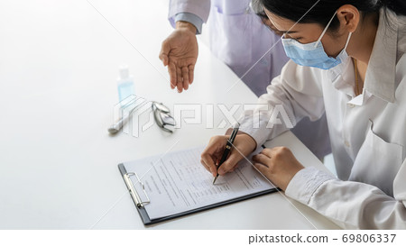 Asian woman wearing protective mask and filling a coronavirus self reporting form. 69806337