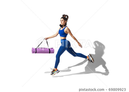 Beautiful young female athlete practicing on white studio background with shadows 69809923