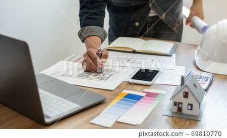 Interior designer choosing color in color swatch samples chart for house coloring selection. Interior designer choosing color in color swatch samples chart for house coloring selection. 69810770