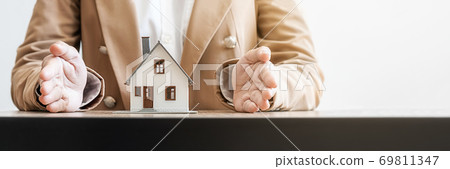 Insurance concept. Agent hand protecting house model that shows to customers to get house insurance. Insurance concept. Agent hand protecting house model that shows to customers to get house insurance. 69811347
