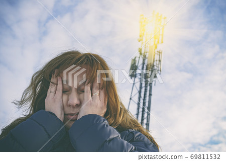 Woman is holding her head near the 5G BTS 69811532