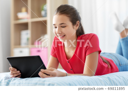 smiling girl with tablet pc lying on bed at home 69811895