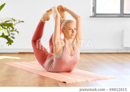 woman doing bow pose at home or yoga studio 69812015