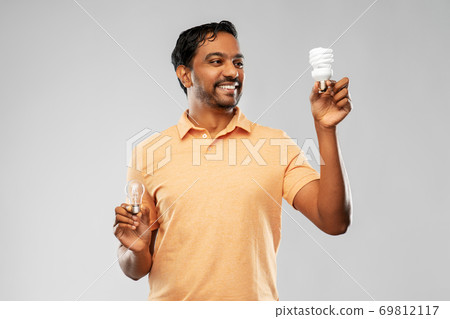 smiling indian man comparing different light bulbs smiling indian man comparing different light bulbs 69812117