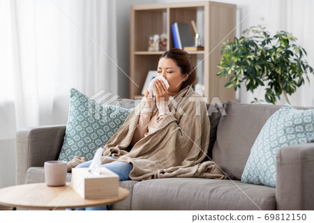 sick asian woman blowing nose with tissue at home sick asian woman blowing nose with tissue at home 69812150
