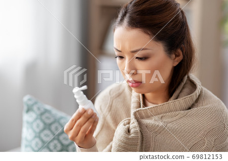 sick asian woman with oral spray medicine at home 69812153