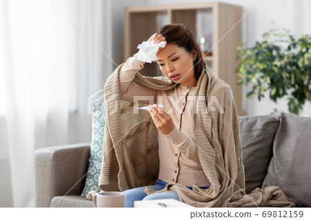 sick woman measuring temperature by thermometer 69812159