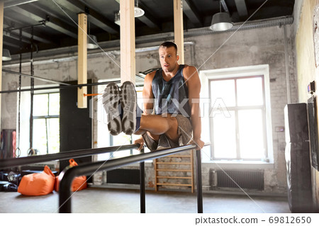 man flexing abs on parallel bars in gym 69812650