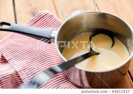 pot with eggnog and ladle on kitchen towel 69812837
