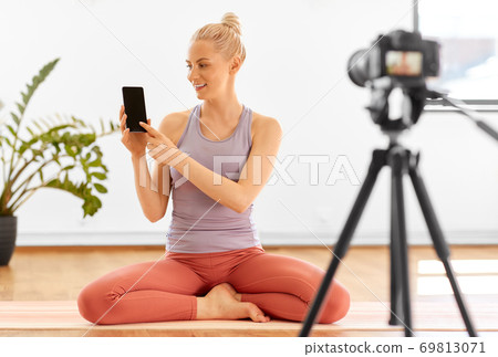 woman with phone streaming for yoga blog at home woman with phone streaming for yoga blog at home 69813071