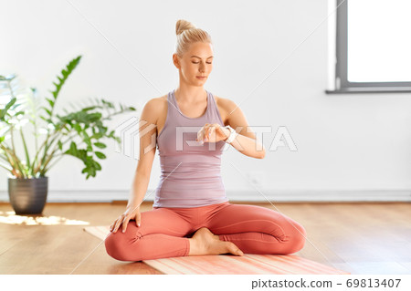 woman with smart watch at home or yoga studio woman with smart watch at home or yoga studio 69813407