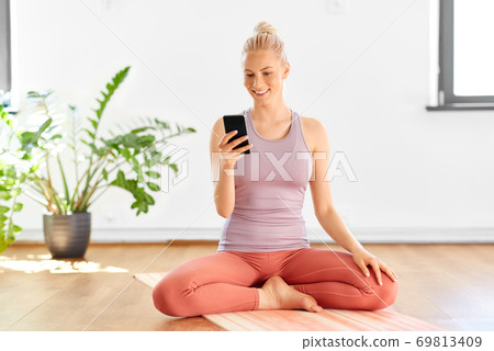 woman with smartphone at home or yoga studio 69813409