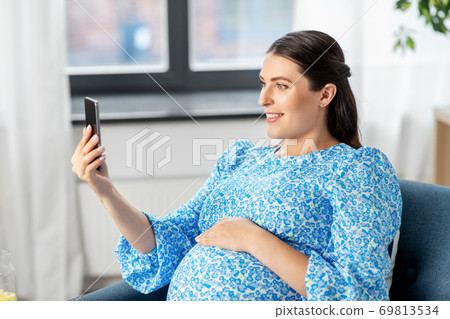 happy pregnant woman with smartphone at home happy pregnant woman with smartphone at home 69813534