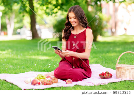 happy woman with smartphone on picnic at park happy woman with smartphone on picnic at park 69813535