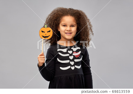 girl in halloween costume with jack-o-lantern 69813559