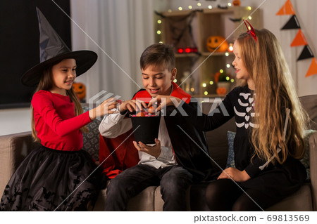 kids in halloween costumes sharing candies at home kids in halloween costumes sharing candies at home 69813569