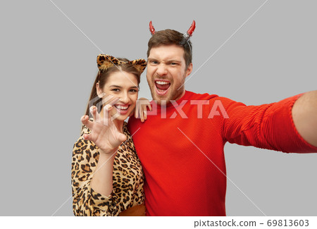 happy couple in halloween costumes taking selfie 69813603