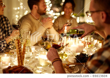 man pouring red wine into glass at christmas party 69813604