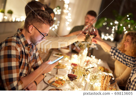man with smartphone at dinner party with friends man with smartphone at dinner party with friends 69813605