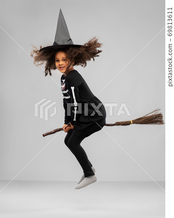 girl in black witch hat with broom on halloween 69813611