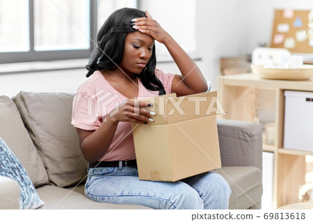 sad african american woman with parcel box at home sad african american woman with parcel box at home 69813618