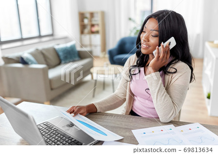 woman with papers calling on phone at home office 69813634