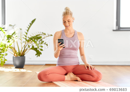 woman with phone and earphones doing yoga at home 69813683