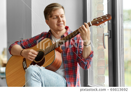 young man playing guitar sitting on windowsill young man playing guitar sitting on windowsill 69813692