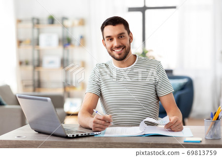 man with papers and laptop working at home office man with papers and laptop working at home office 69813759