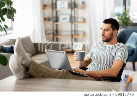 man with laptop drinking coffee at home 69813770