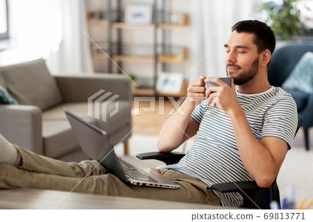 happy man with laptop drinking coffee at home happy man with laptop drinking coffee at home 69813771
