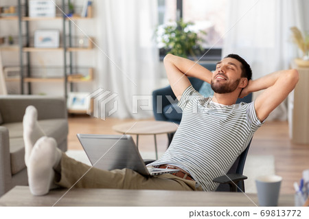 happy man with laptop resting at home office 69813772