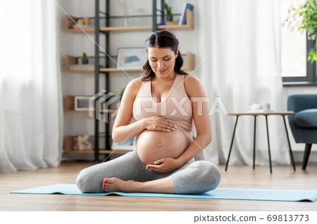 happy pregnant woman doing yoga at home happy pregnant woman doing yoga at home 69813773