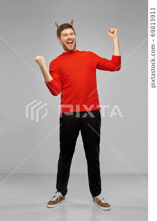 happy man in costume of devil celebrating success 69813911