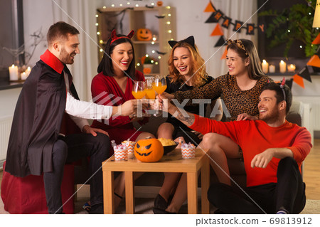 happy friends in halloween costumes at home party 69813912