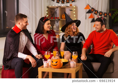 happy friends in halloween costumes at home party 69813914