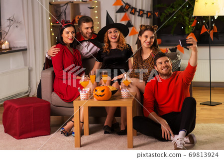 happy friends in halloween costumes taking selfie 69813924
