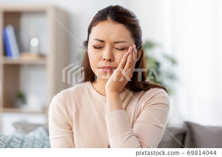 unhappy woman suffering from toothache at home 69814044