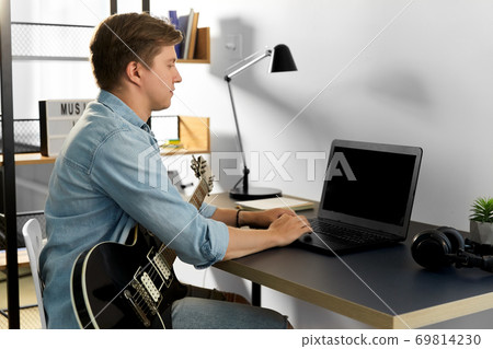 young man with laptop and bass guitar at home young man with laptop and bass guitar at home 69814230