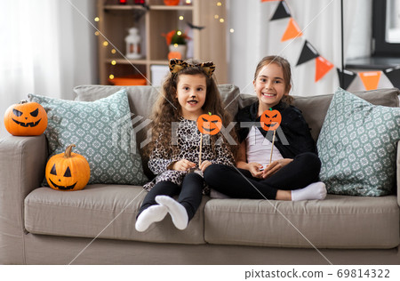 girls in halloween costumes with pumpkins at home 69814322