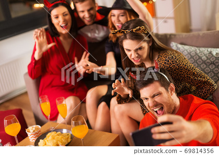 happy friends in halloween costumes taking selfie 69814356