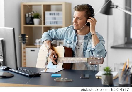 man in headphones playing guitar at home 69814517