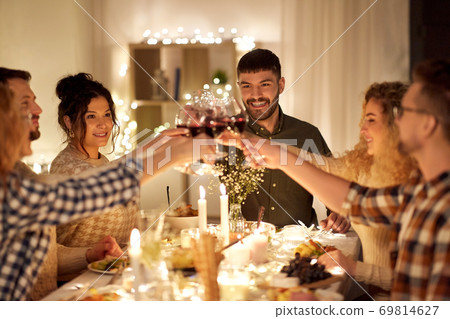 happy friends drinking red wine at christmas party 69814627