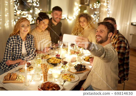 friends taking selfie at christmas dinner party 69814630