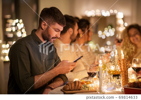 man with smartphone at dinner party with friends 69814633