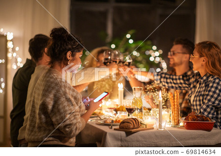 woman with smartphone at dinner party with friends woman with smartphone at dinner party with friends 69814634